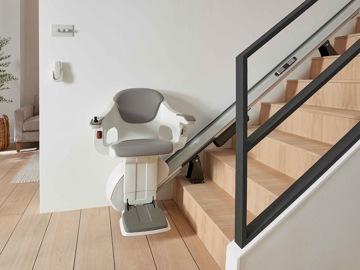 Sitzlift SL Classic mit grauem Sitz an einer geraden Treppe mit dunklem Gel&auml;nder